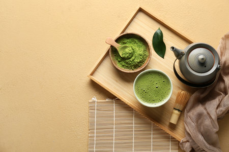Composition with wooden tray, bowl of tasty matcha tea and teapot on beige grunge backgroundの写真素材
