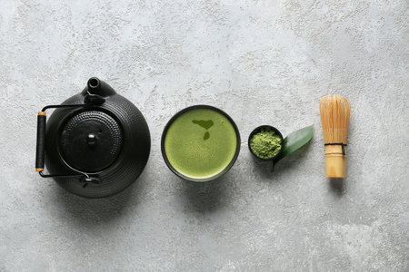 Cup of matcha tea, teapot, chasen and powder on gray grunge backgroundの写真素材