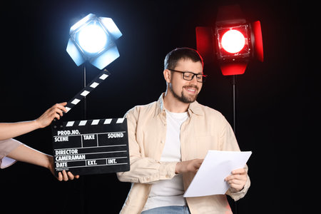 Male actor and female hands with movie clapper on dark backgroundの写真素材