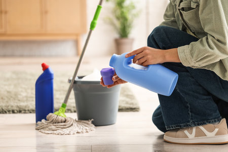 Woman pouring detergent before mopping floor in roomの写真素材