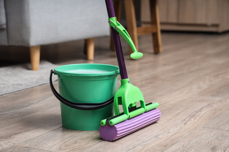 Mop with green bucket of water on floor in living room