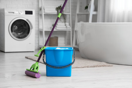 Mop with blue bucket of water on floor in bathroomの写真素材