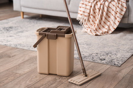 Mop with beige bucket on floor in living roomの写真素材