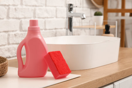 Cleaning sponge with bottle of detergent on table in bathroom, closeupの写真素材