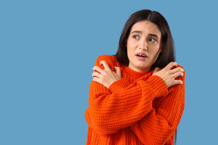 Scared young woman on blue backgroundの写真素材