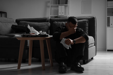 Businessman with crumpled paper and gun on table in dark office. International Stress Awareness Weekの写真素材