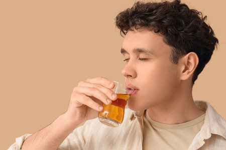 Young man drinking Turkish tea on beige background, closeupの写真素材