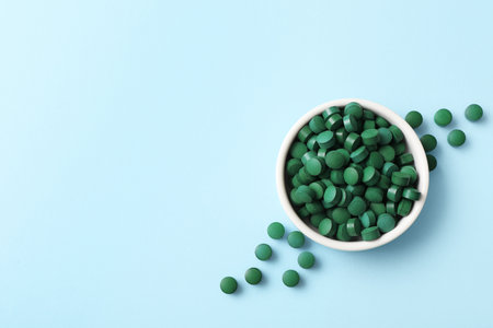 Bowl of spirulina tablets on blue backgroundの写真素材