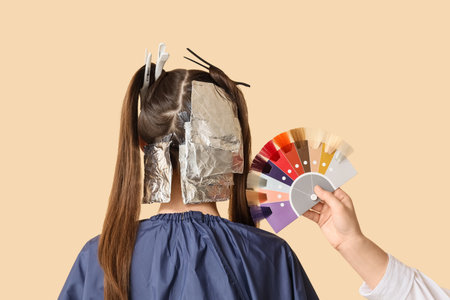 Female hairdresser's hand with hair color palette and client on beige background, back viewの写真素材