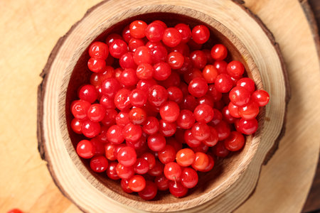 Bowl with fresh viburnum berries on wooden board, closeupの写真素材