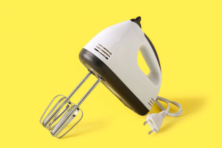 Electric mixer on yellow background
