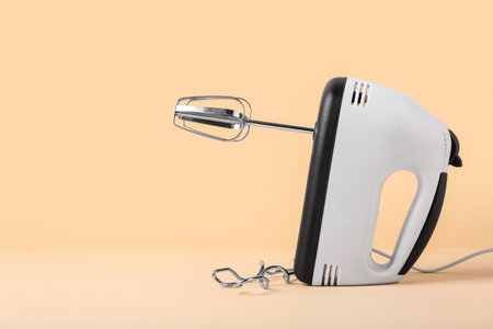 Electric mixer with chrome beaters on beige backgroundの写真素材