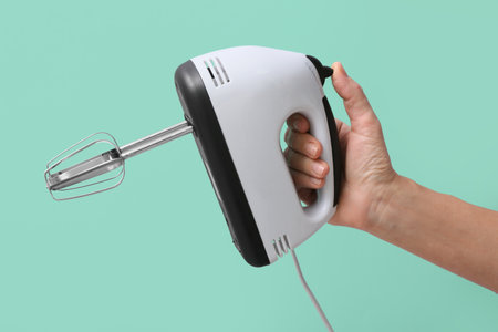 Woman holding electric mixer on turquoise backgroundの写真素材