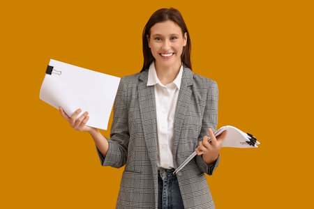 Young businesswoman with papers on yellow background