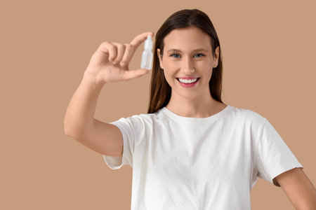 Young woman with eye drops on beige background