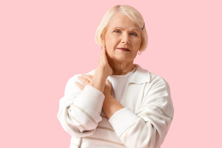 Senior woman in sweatshirt on pink background