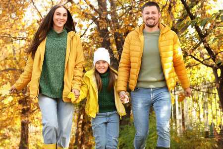 Little girl with her parents running in autumn parkの写真素材