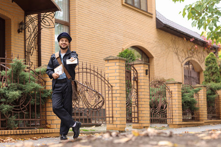 Handsome postman with letters on streetの写真素材