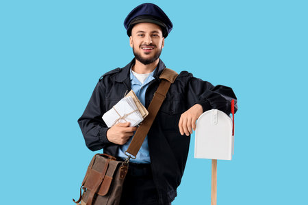 Handsome postman with letters and mailbox on blue backgroundの写真素材