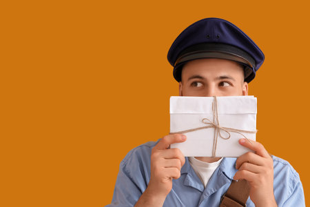 Handsome postman with letters on yellow backgroundの写真素材