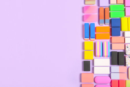 Different colorful rubber erasers on purple background