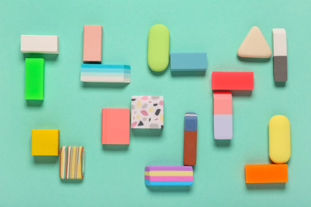 Different colorful rubber erasers on turquoise background