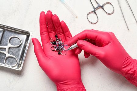 Piercing jewelry selection with gloved hands and sterilized tools for body modification procedure, body modification and personal expression are central to this image