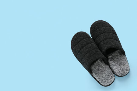 Soft black slippers on blue background