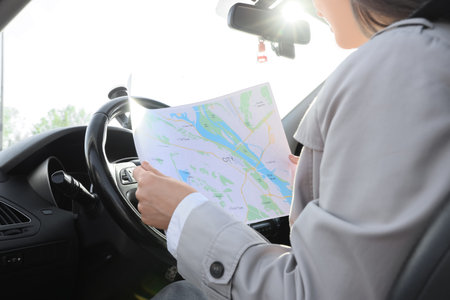 Woman driver navigating city streets with paper map, road trip planning and travel direction guidance