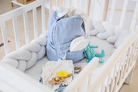 Baby essentials in a crib with blue backpack and toys