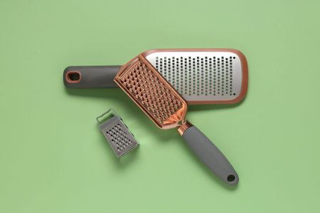 Three kitchen graters on green background