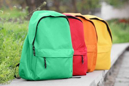 Colorful backpacks on concrete ledge in park