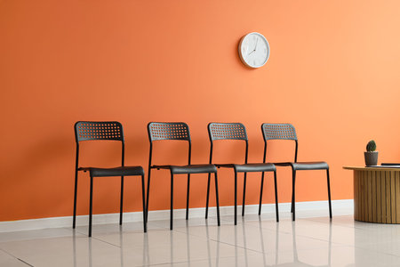 Empty waiting room with black chairs and orange wall