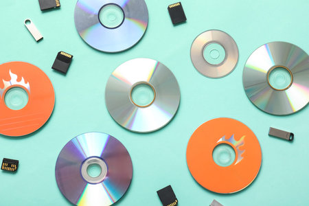 Composition with CD disks, USB flash drives and SD cards on turquoise background