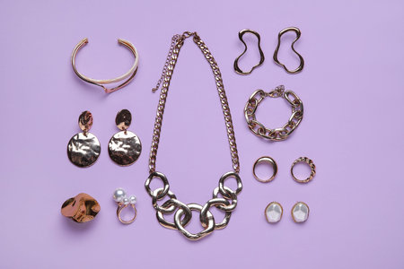Stylish female accessories on lilac background
