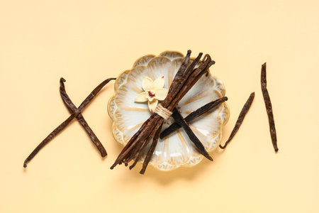 Plate with gourmet vanilla pods and beautiful flower on beige background