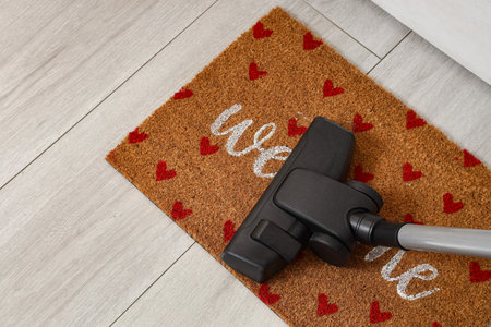 Vacuum cleaner on doormat in hallway, top view