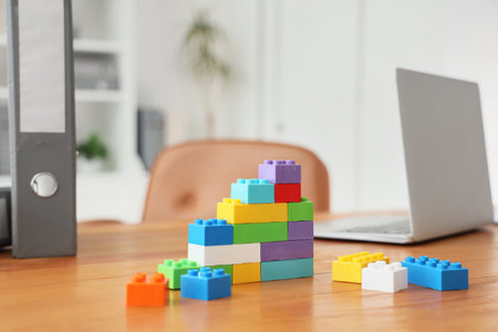 Business growth and development concept, colorful building blocks on an office desk with a laptop and binder