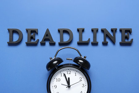 Word DEADLINE with alarm clock on blue background