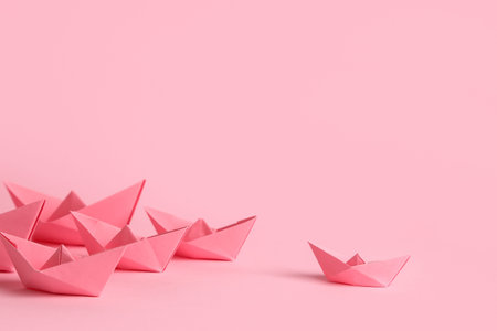 Many origami boats on pink background