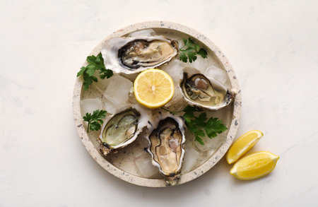 Plate with delicious fresh oysters, lemon and parsley on white background