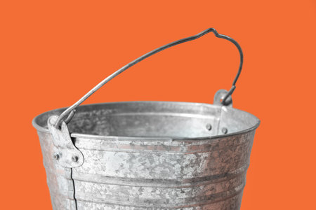 Galvanized metal bucket on orange background