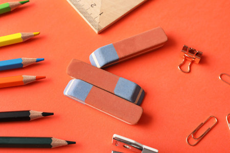 Erasers with stationery on orange background