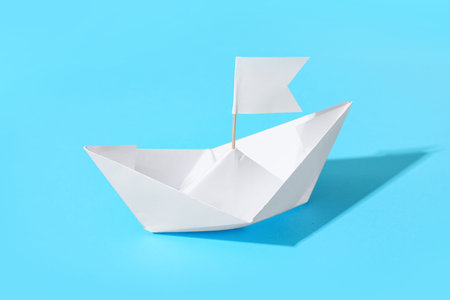 White paper boat with flag on blue background
