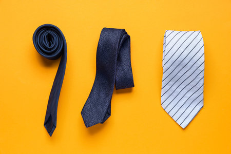 Stylish male ties on orange background