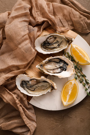 Fresh raw oysters with lemon and thyme on marble and wood board, gourmet seafood delicacy, fresh raw oysters are presented with bright lemon wedges and aromatic thyme sprigs