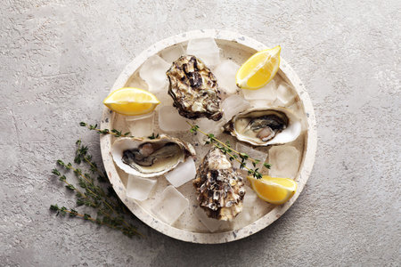 Fresh raw oysters on ice with lemon wedges and thyme sprigs, gourmet seafood delicacy appetizer