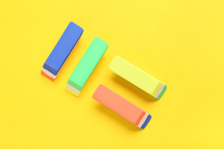 Different rubber erasers on yellow background