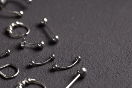 Body piercing and fashion accessories, collection of silver metal jewelry for ear and nose on dark textured background