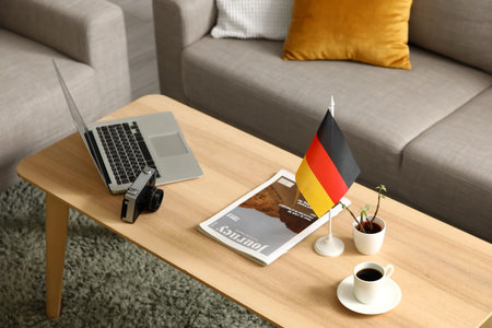 German flag with magazine, coffee and laptop on table in living room